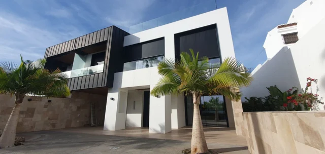 Imagen de la fachada de una vivienda de dos plantas de estilo modernista con dos palmeras en la entrada principal