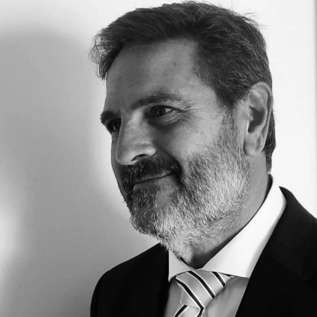 Imagen en blanco y negro de Salvador Romano con mirada afable y natural mientras mira hacia un lateral de su oficina